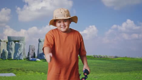 asian boy with a hat dancing after looking through the binoculars. boy researcher examines something while traveling in stonehenge, travel tourism adventure concept