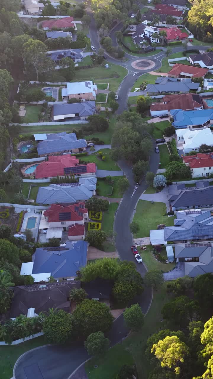 Ripresa aerea con drone cattura case suburbane e alberi verdi lussureggianti nel Queensland durante il tramonto