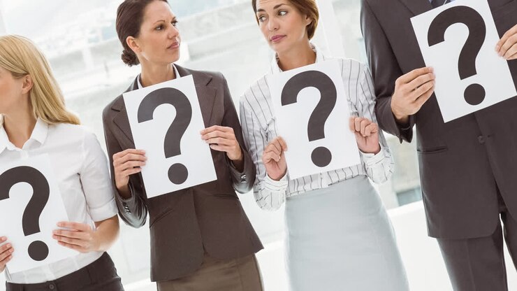Confused group of caucasian businessmen and businesswomen holding question mark signs