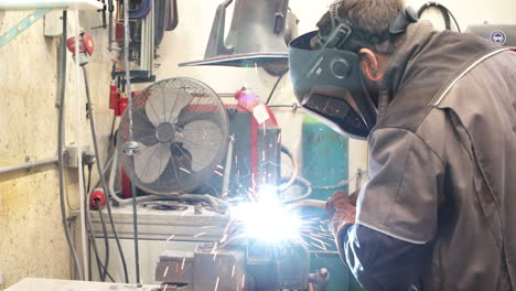 worker welding steel tube with a mig welder