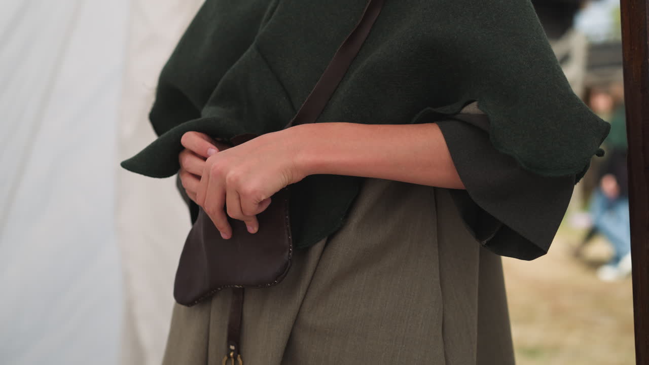 женщина прячет небольшую бутылку с колдовским зельем в сумочке.