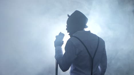 silhouette of a man singing into a microphone on stage