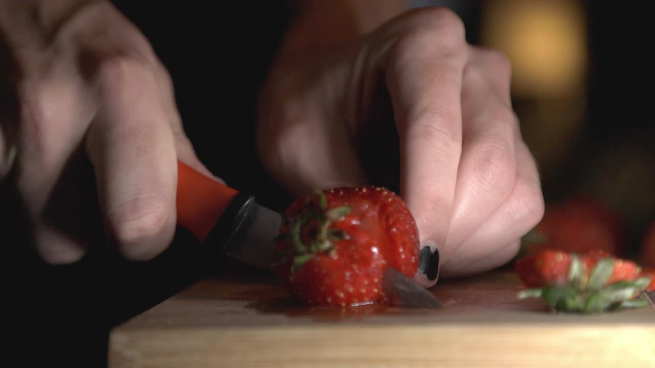 Person Cutting And Slicing Red Strawberry In The Kitchen Using A Sharp Knife. - close up shot