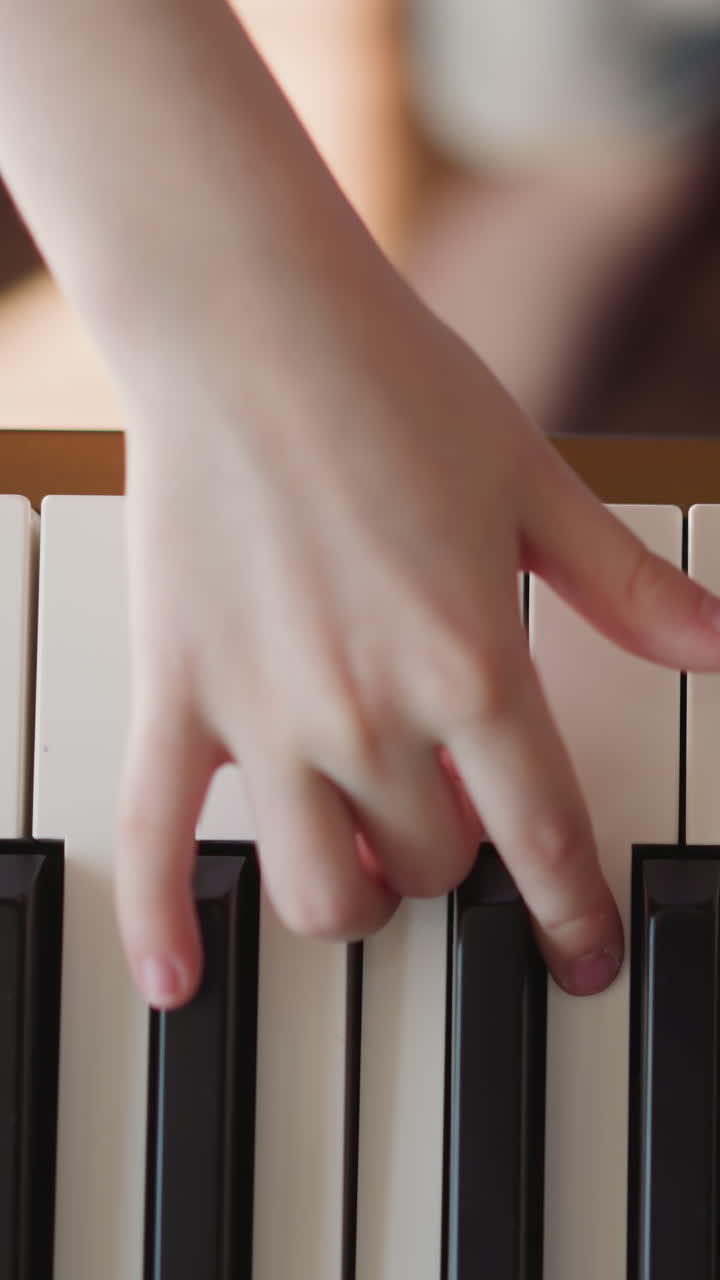 Kid hands play electric piano practicing legato articulation. Girl plays song pressing keys diligently. Musical performance upper view on blurred background