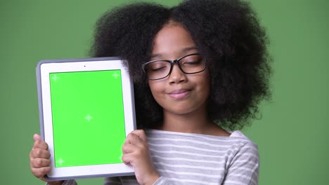 young cute african girl with afro hair showing digital tablet to camera