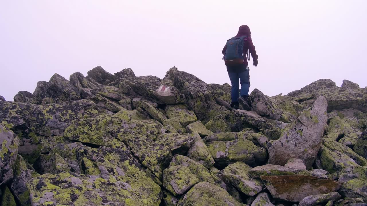 excursionistas caminando por la ladera de una montaña en la ladera rocosa de rumania
