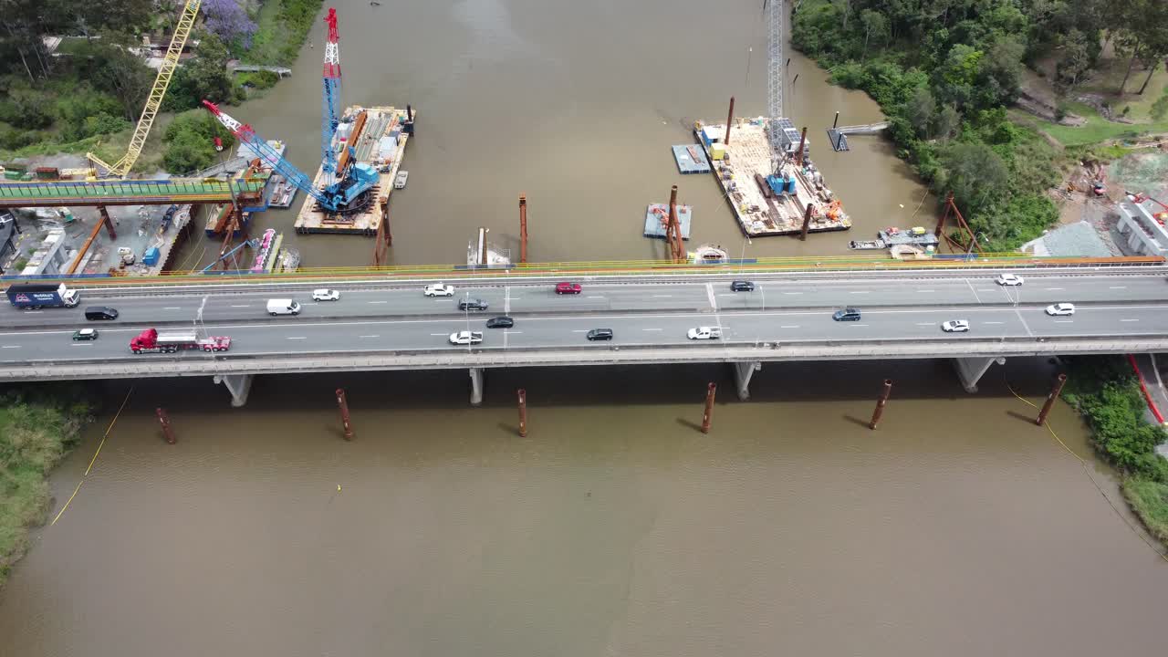 4K aerial view of a bridge over a brown river and a new bridge under construction next to it