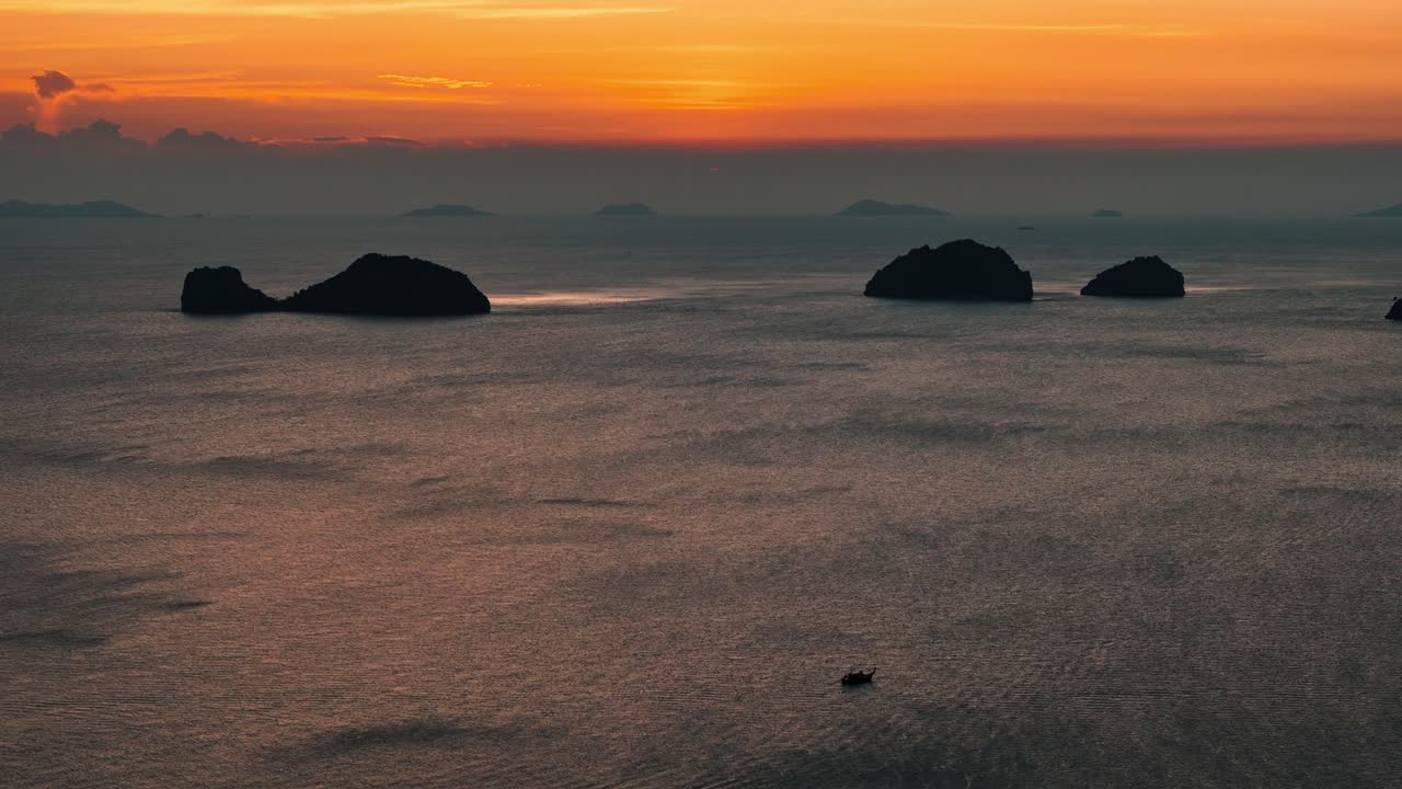 해가 지는 동안 떠다니는 바다, 멀리 있는 여러 섬, 그리고 작은 배.