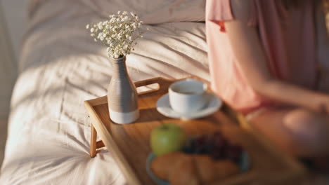 female hands holding smartphone in sunny bed closeup. hotel room breakfast table