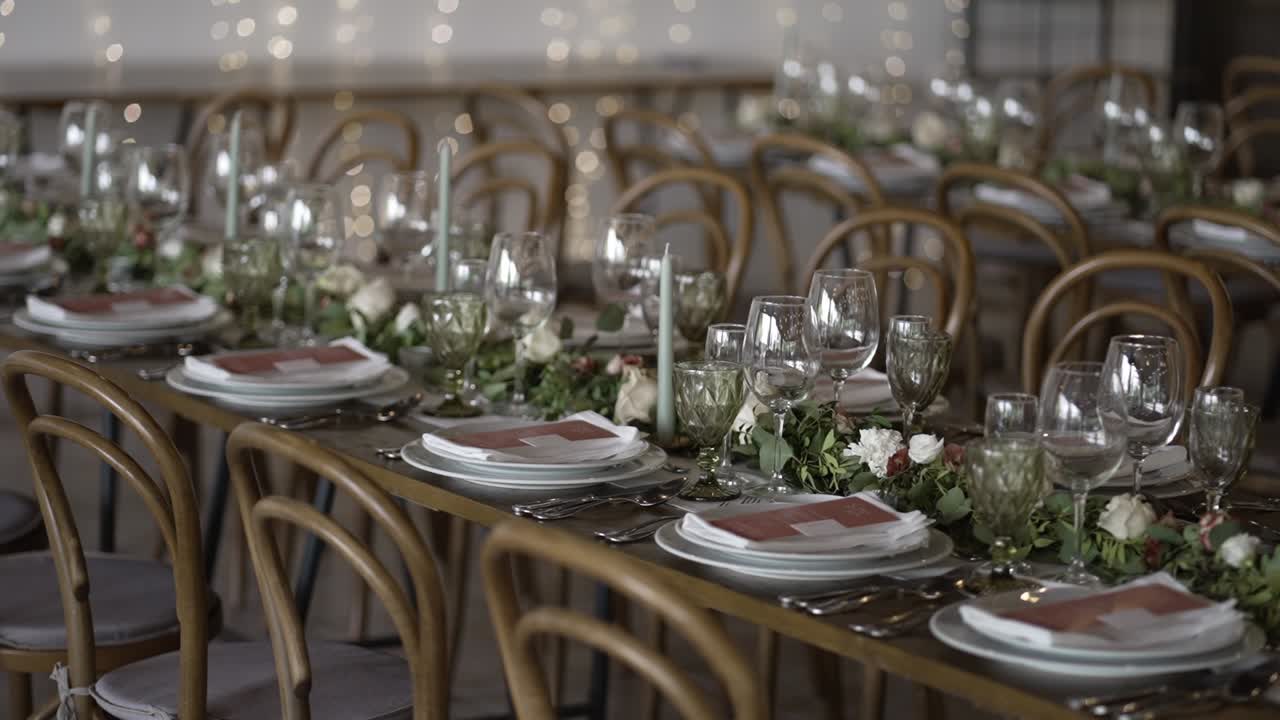 Elegant dekkede bryllupsbord med blomstergirlandere, levende lys og glitrende glass