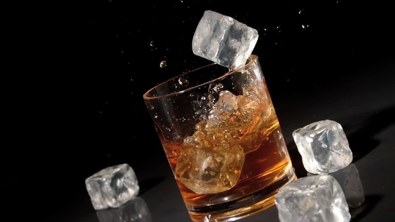 tres cubos de hielo cayendo en un vaso de whisky y hielo