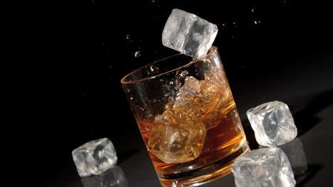 three ice cubes falling into tumbler of whiskey and ice