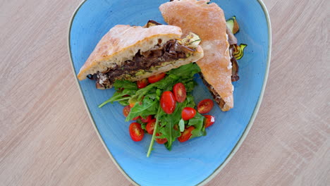 ojo de pájaro vista giratoria lenta del delicioso pan de sándwich ciabatta, berenjenas a la parrilla, calabacín y tomates cherry en el plato