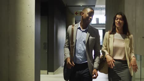 Diverse-businessman-and-businesswoman-talking-in-corridor-of-modern-office