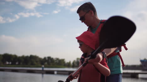 father teaching son how to kayak