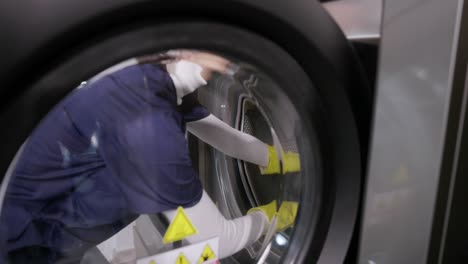 trabajador de la lavandería cargando el cobertizo en la máquina de lavar de carga delantera