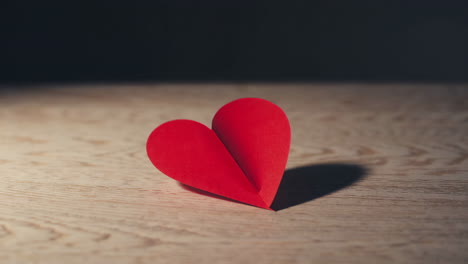red origami heart on wooden surface