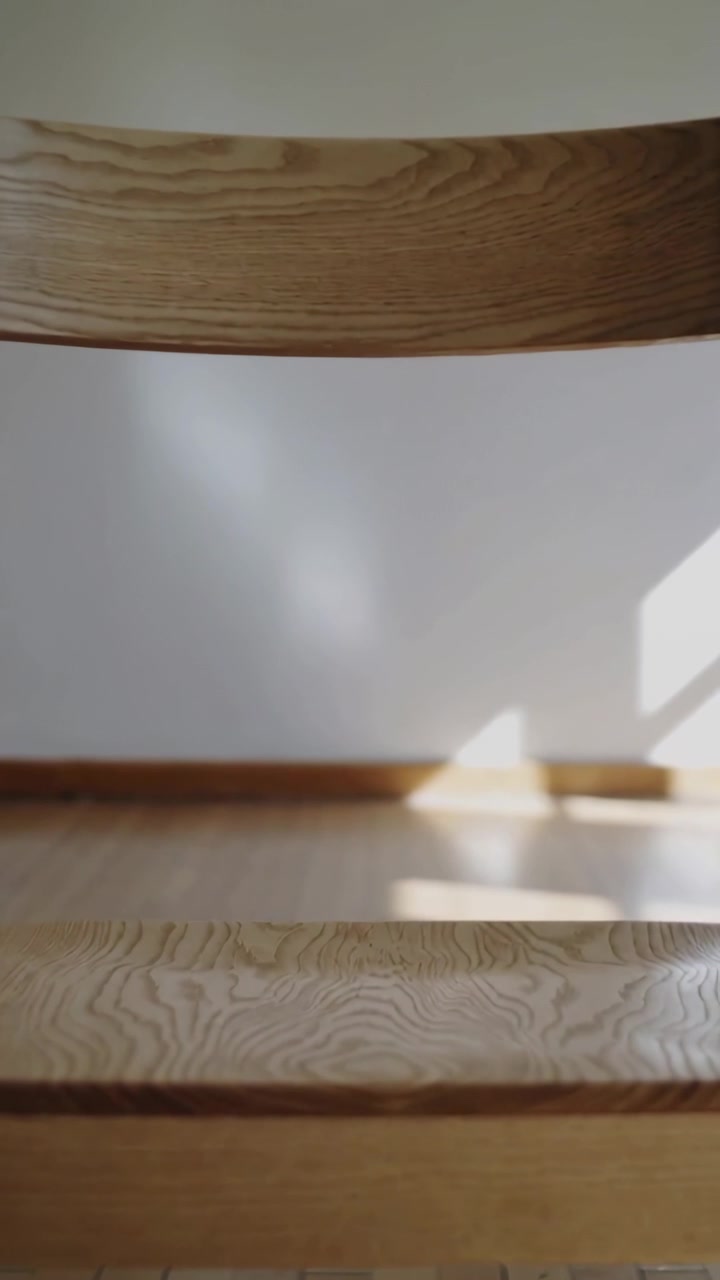 Video verticale: Telecamera a mano che si inclina e si muove riprendendo una sedia di legno a casa, rivelando lo schienale.