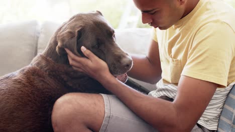 hombre feliz de dos razas acariciando a su perro en casa, cámara lenta