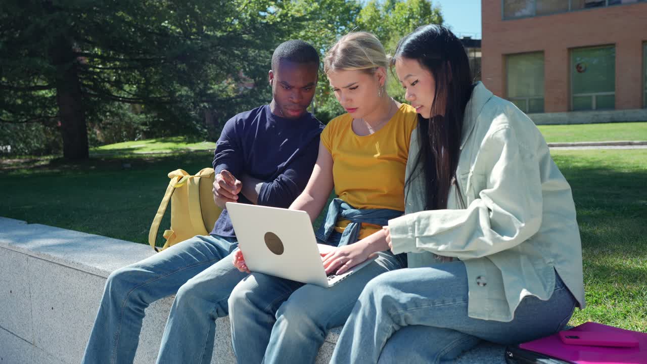 Studerende, der arbejder sammen på bærbar computer udendørs