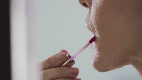 close up of the mouth and chin of a fashion model applying her lip gloss to her lips