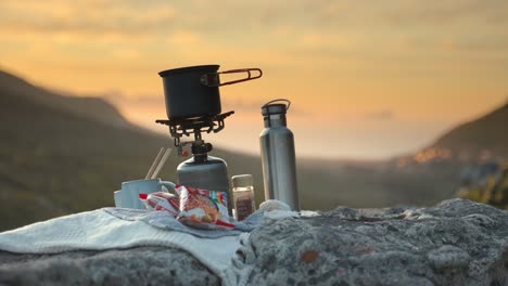 portable stove and saucepan on rock, set against stunning scenic landscape in england, uk, with idyllic sunset sky