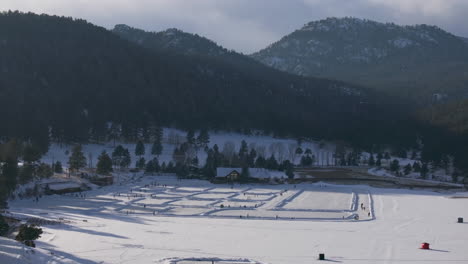 Ice-skating-skate-hockey-rink-lake-pond-hockey-winter-Etown-Evergreen-Lake-house-Denver-golf-course-Colorado-aerial-cinematic-drone-sunset-golden-hour-winter-fresh-snow-slow-pan-up-forward-motion