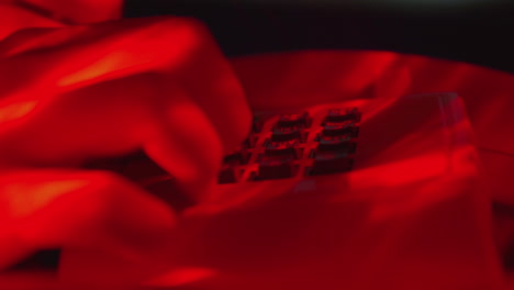 dedo masculino marcando un número de teléfono para hacer una llamada telefónica en un teléfono de escritorio blanco clásico en una habitación con luz roja