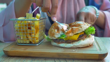 woman eating a cheeseburger and fries