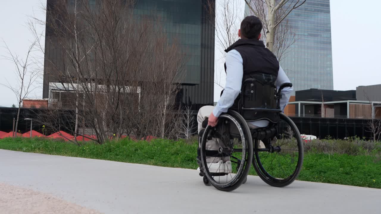 Mladý muž na invalidním vozíku jedoucí po městské stezce