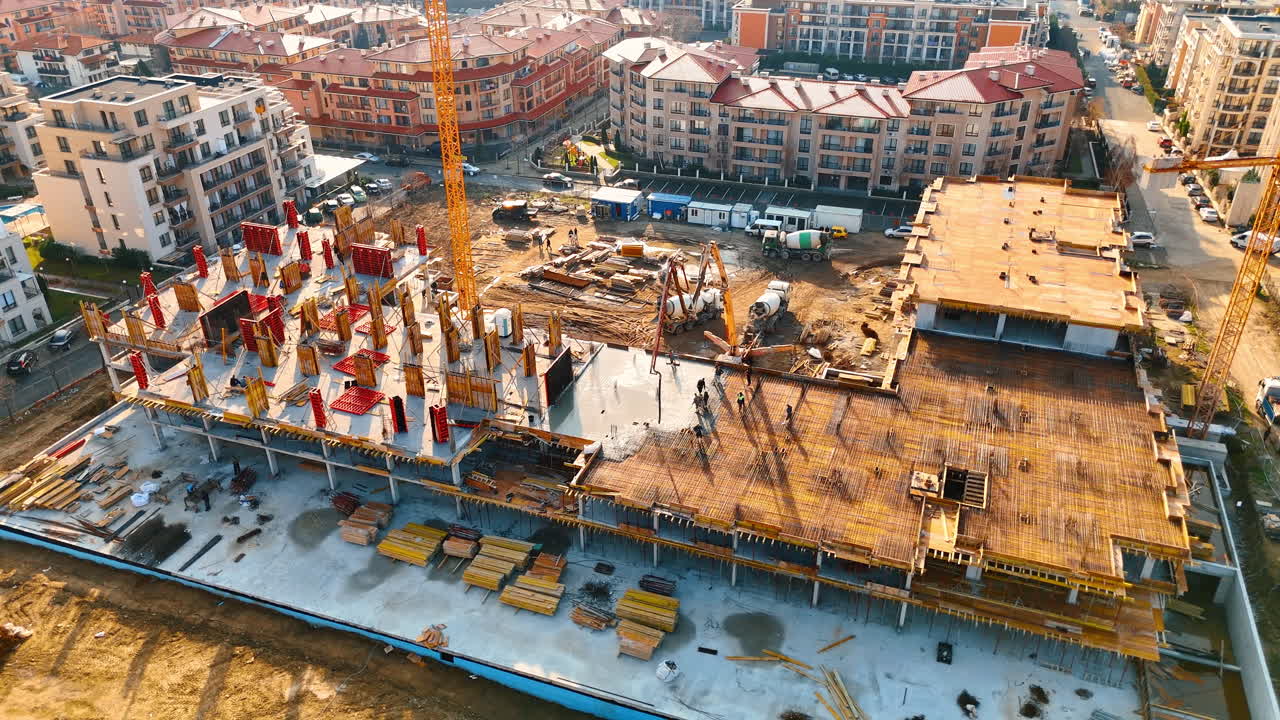 Close up aerial view of concrete pouring on construction site. Detailed shot of building structure with workers and concrete pumps
