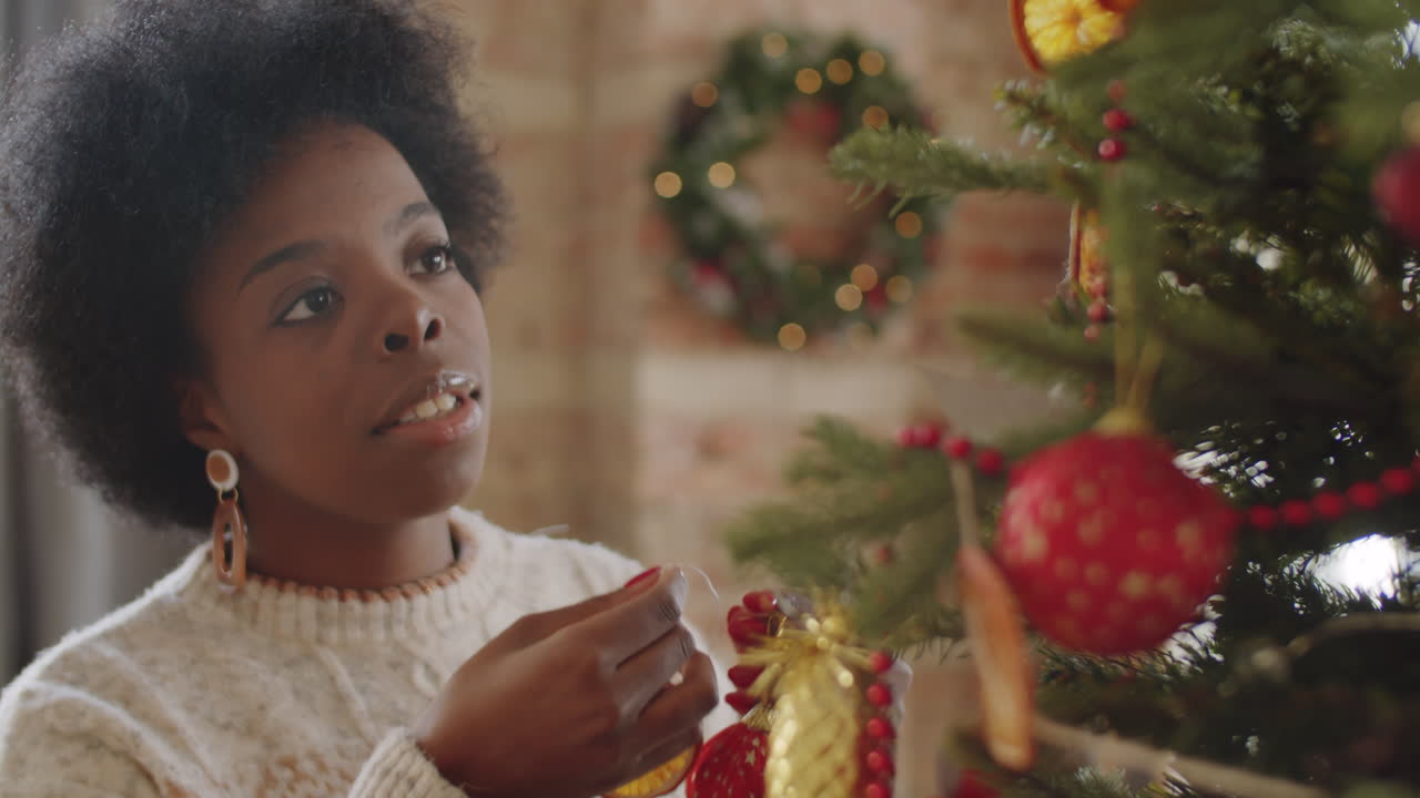 mujer afroamericana decorando el árbol de navidad en casa