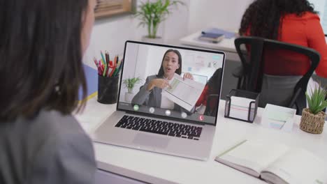 video de una mujer caucásica haciendo una videollamada en una computadora portátil con una compañera de trabajo biracial