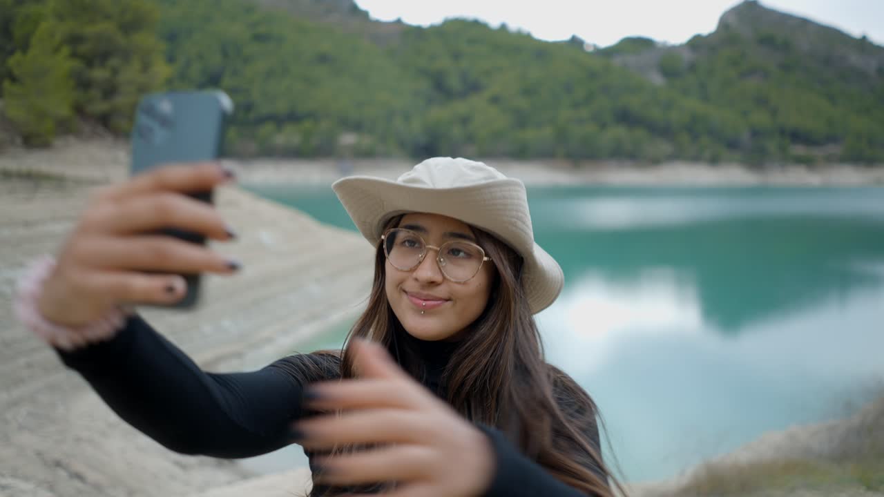 una mujer tomando una selfie junto a un lago.