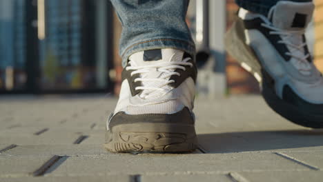 close up of cigarette being crushed under white and black sneaker as person stands on pavement during sunny day, symbolic act of quitting smoking with blurred urban background