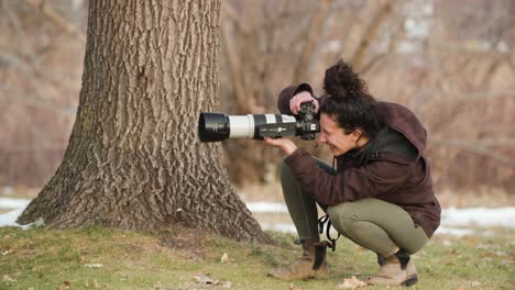 una mujer fotógrafa de vida silvestre está filmando junto a un roble en un parque de la ciudad