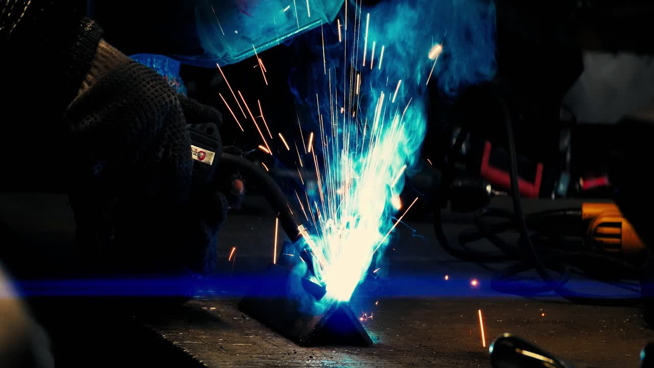 금속 용접공은 보호 장비를 갖춘 공장에서 강철 용접공과 함께 일합니다