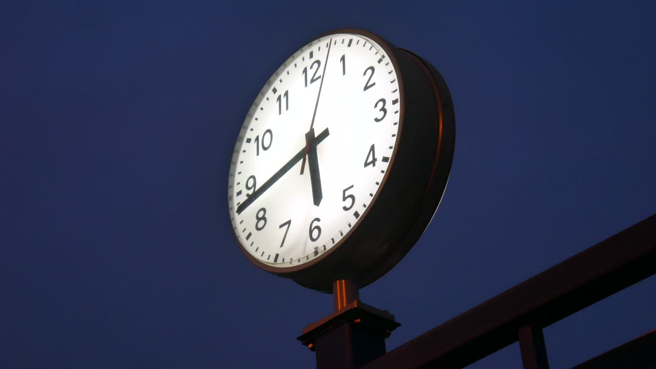 View on a train station clock at night as the seconds are passing.