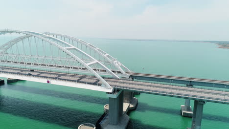 aerial view of a modern arch bridge over a turquoise river