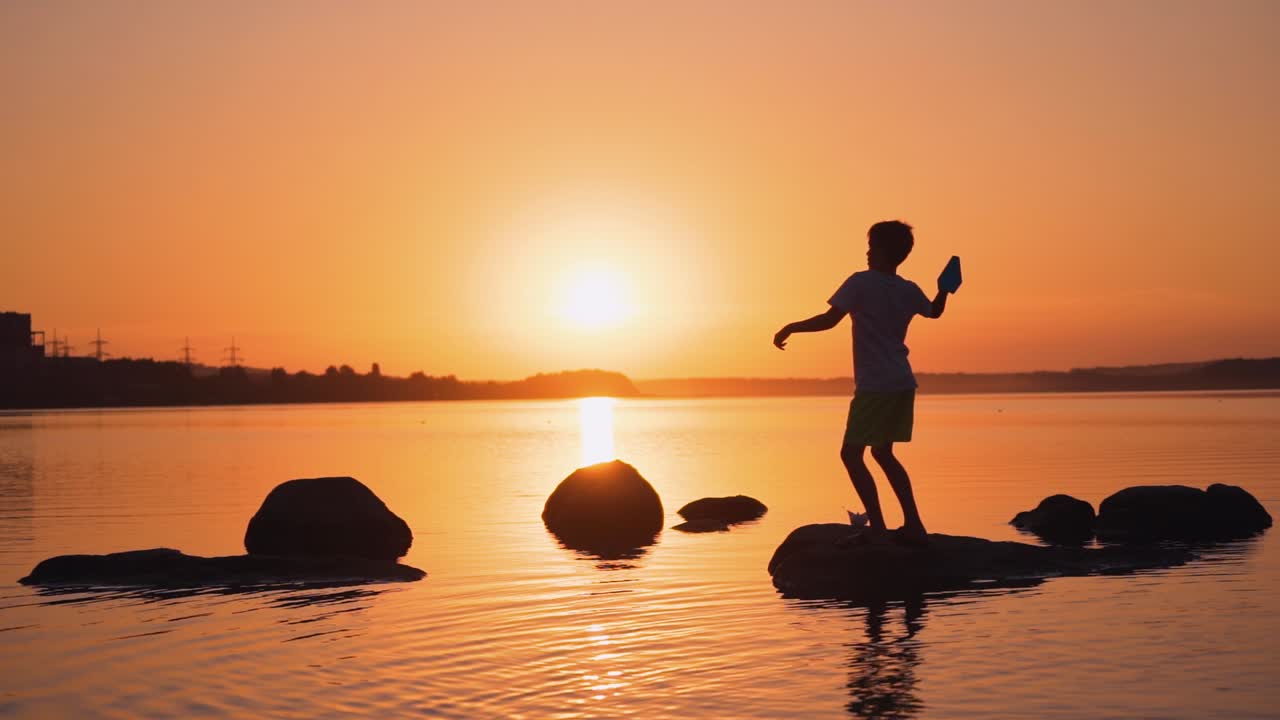 Little boy with paper plane. Beautiful sunset. Origami.