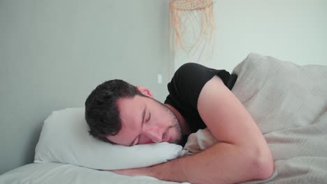 sleeping man, caucasian white with beard, young man lying in bed sleeping dreaming, uncomfortable pillow, turn over in sleep