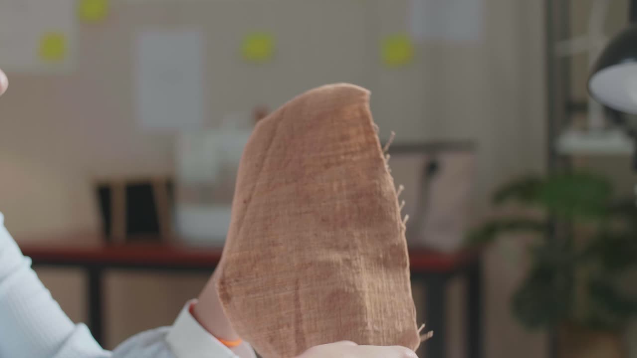 손에 든 직물을 바라보는 아시아 여성 디자이너의 클로즈업