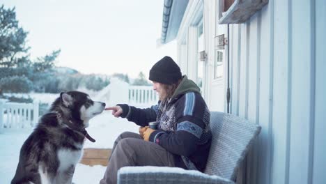 a gentleman enjoys a warm drink while seated with his alaskan malamute in indre fosen, trondelag county, norway - static shot