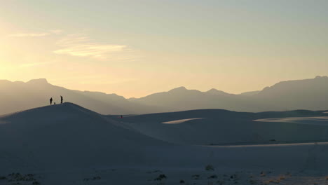 wide sunset view of people standing on sand dunes in white sands national park