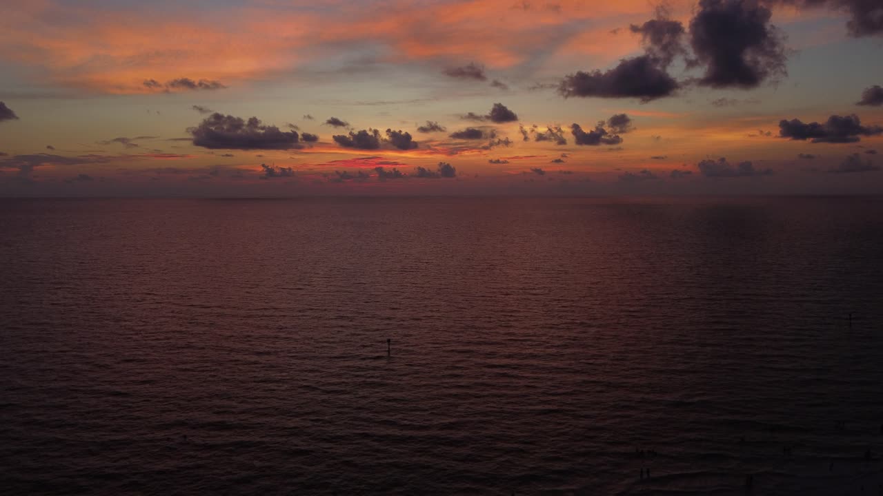 Aerial drone shot of sunset in Florida with beach, ocean and people. Crane up movement.