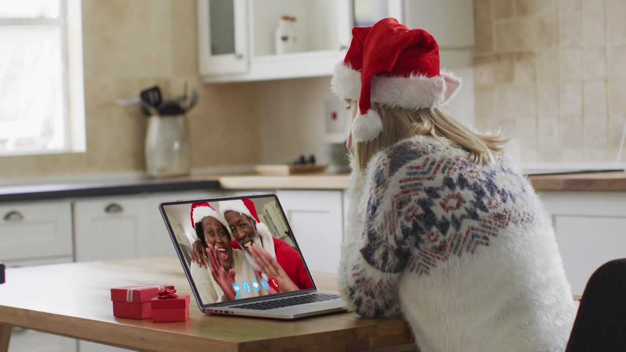 mujer caucásica con sombrero de papá noel en una videochat portátil durante la navidad en casa