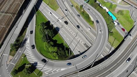 round circular european asphalt highway off and on ramp, cars and traffic traveling on expressway and entering and exiting on sunny day, static overhead