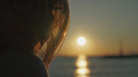 attractive young woman smiles at camera then turns to enjoy sunset