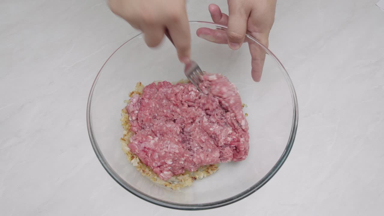 Ground meat placed and spread in glass bowl before mixing during food preparation