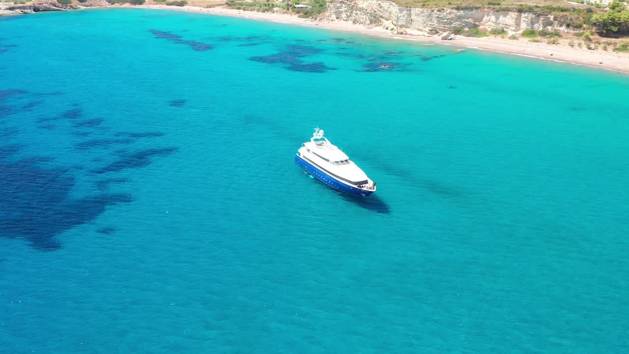 Yacht di lusso blu e bianco ormeggiato vicino a una spiaggia paradisiaca, Grecia.